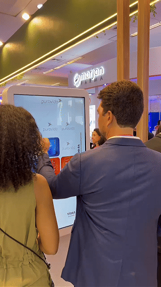 Imagem do estande Puravida no Congresso de Nutrologia, com visitantes participando do jogo da memória digital desenvolvido pela Phygital Solutions.