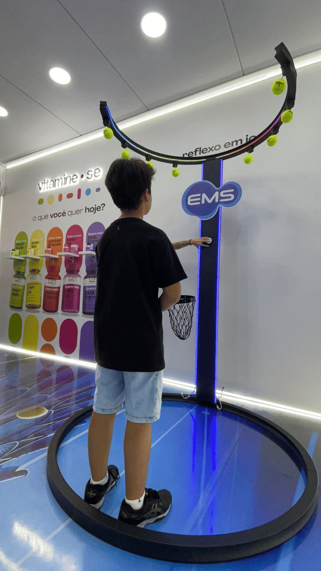 Ativação Reaction Ring no espaço da EMS durante o RIO OPEN 2026, com participante dentro da estrutura semicircular interativa enquanto o público acompanha ao redor em ambiente de evento esportivo.