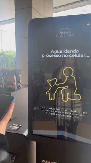 Totem interativo da ativação Nestlé Purina com QR Code para envio de fotos pelo celular. A experiência utilizava inteligência artificial para gerar uma imagem personalizada do tutor ao lado do seu pet, com resultado final direcionado para impressão.
