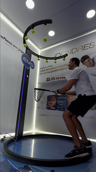 Ativação Reaction Ring no espaço da EMS durante o RIO OPEN 2026, com participante dentro da estrutura semicircular interativa enquanto o público acompanha ao redor em ambiente de evento esportivo.