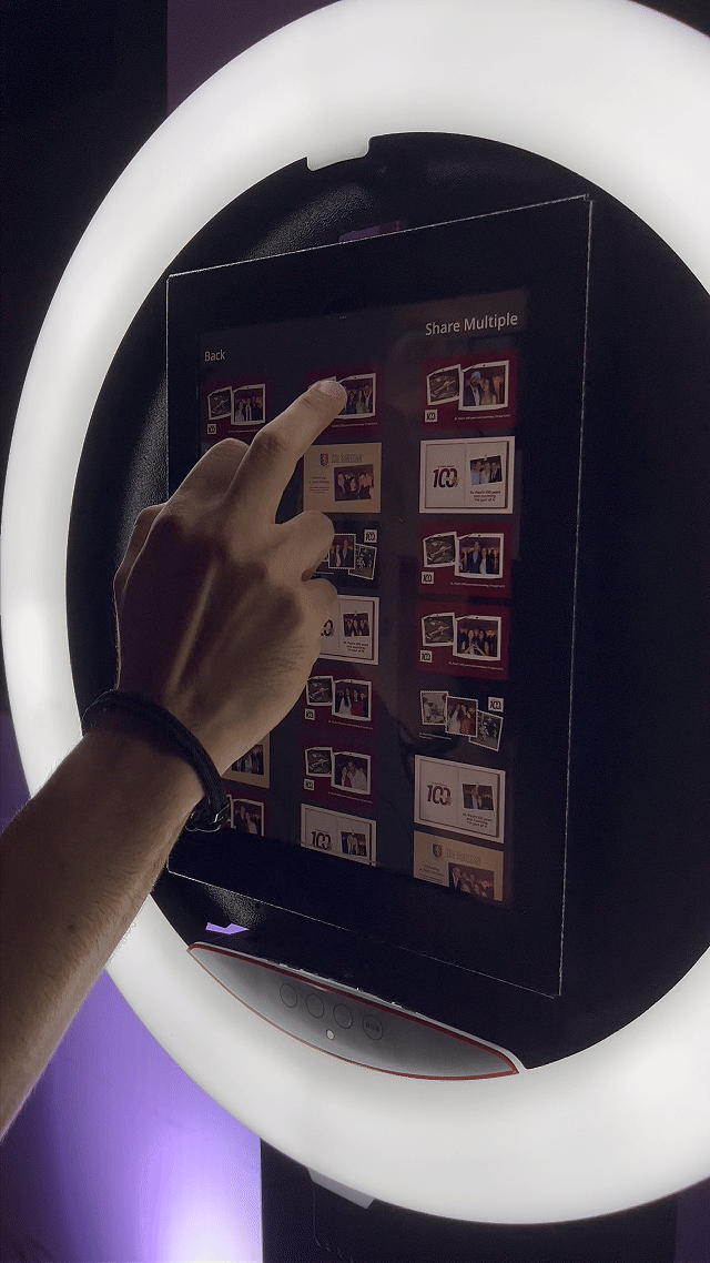 Totem Capture Booth instalado no evento de Centenário do St. Paul’s School, com participante posando para foto e impressão instantânea 10x15 sendo realizada no local.