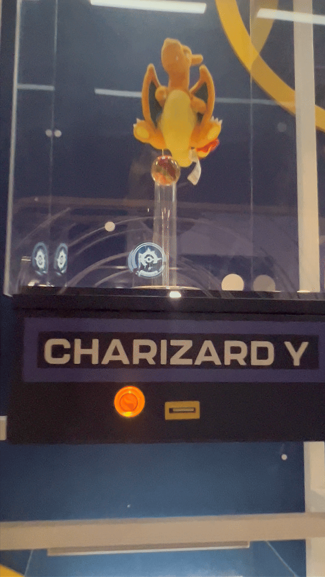 Visitantes interagem na ativação Pokémon Company | BGS 2025 – Experiência Megaevolução. Totens digitais da Phygital Solutions exibem o processo de escolha do Pokémon e da Mega Evolução, com público participando, cartões personalizados e iluminação temática do estande.