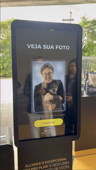 Totem interativo da ativação Nestlé Purina com QR Code para envio de fotos pelo celular. A experiência utilizava inteligência artificial para gerar uma imagem personalizada do tutor ao lado do seu pet, com resultado final direcionado para impressão.