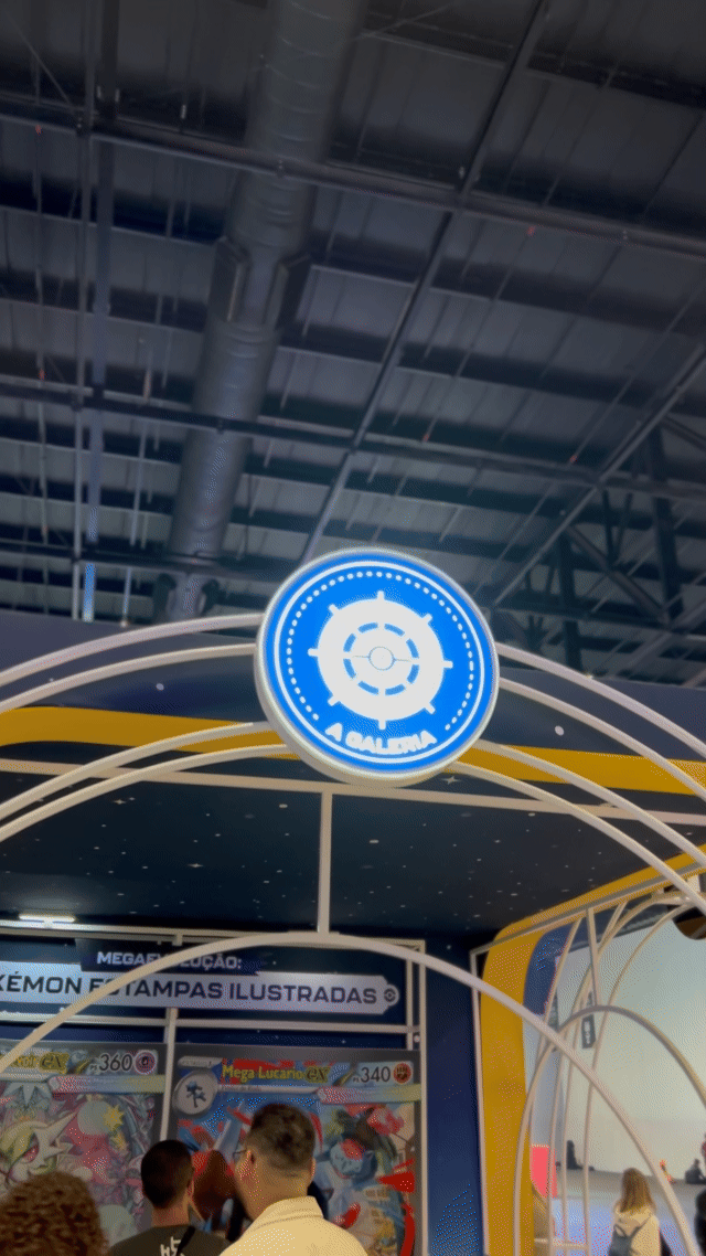 Visitantes interagem na ativação Pokémon Company | BGS 2025 – Experiência Megaevolução. Totens digitais da Phygital Solutions exibem o processo de escolha do Pokémon e da Mega Evolução, com público participando, cartões personalizados e iluminação temática do estande.