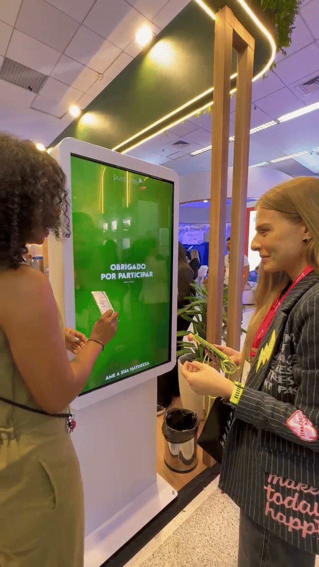 Imagem do estande Puravida no Congresso de Nutrologia, com visitantes participando do jogo da memória digital desenvolvido pela Phygital Solutions.