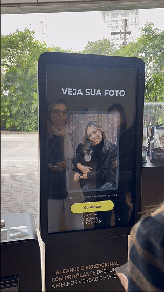 Totem interativo da ativação Nestlé Purina com QR Code para envio de fotos pelo celular. A experiência utilizava inteligência artificial para gerar uma imagem personalizada do tutor ao lado do seu pet, com resultado final direcionado para impressão.