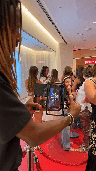 Participantes interagem com ativação Câmera Sign durante a inauguração da loja H&M no Shopping Rio Sul, criando vídeos personalizados com assinatura digital diretamente na lente da câmera.