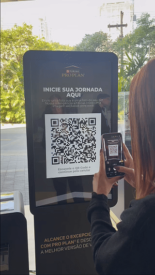 Totem interativo da ativação Nestlé Purina com QR Code para envio de fotos pelo celular. A experiência utilizava inteligência artificial para gerar uma imagem personalizada do tutor ao lado do seu pet, com resultado final direcionado para impressão.