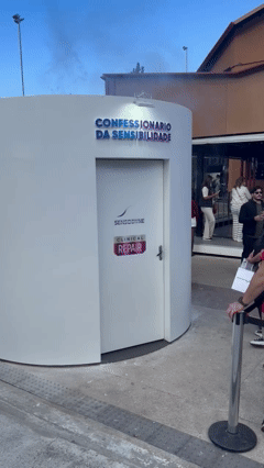 Participante grava vídeo estilo confessionário dentro de estrutura cenográfica da Sensodyne, com tela touch e sistema Phygital que exibe frases em tempo real em uma Social Wall externa durante o Festival de Inverno de Campos do Jordão.