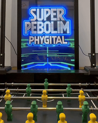Mesa de Pebolim AI Phygital em ambiente de evento, com visual esportivo inspirado na Copa do Mundo e experiência interativa com inteligência artificial.