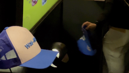 Visitantes interagem com o Museu RFID do Seu Boné na Brazil Promotion 2025, posicionando bonés históricos com tags RFID sobre suporte personalizado produzido em impressoras 3D pela Phygital Solutions, revelando histórias e curiosidades em tempo real.