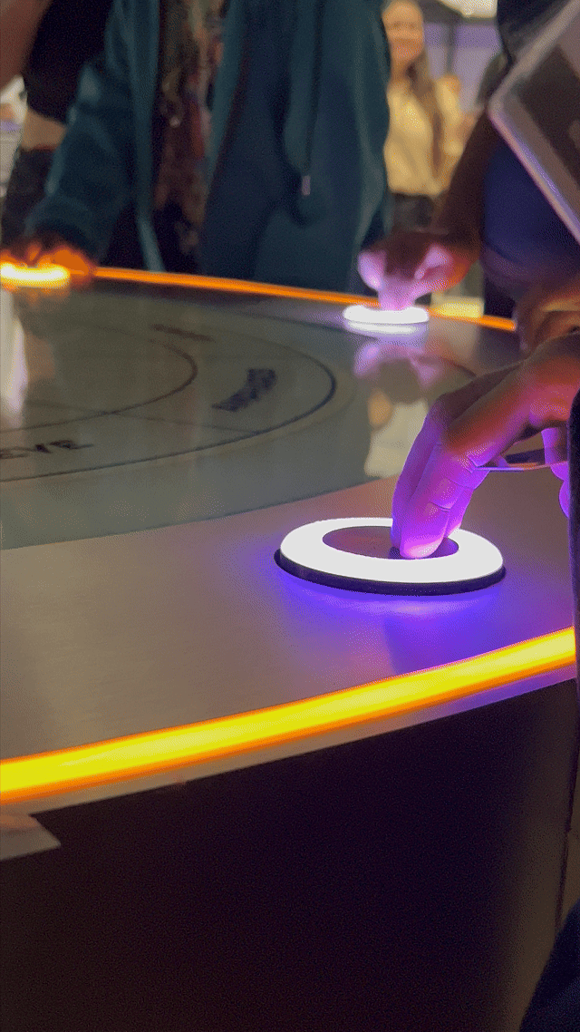 Visitantes interagem na ativação Pokémon Company | BGS 2025 – Experiência Megaevolução. Totens digitais da Phygital Solutions exibem o processo de escolha do Pokémon e da Mega Evolução, com público participando, cartões personalizados e iluminação temática do estande.