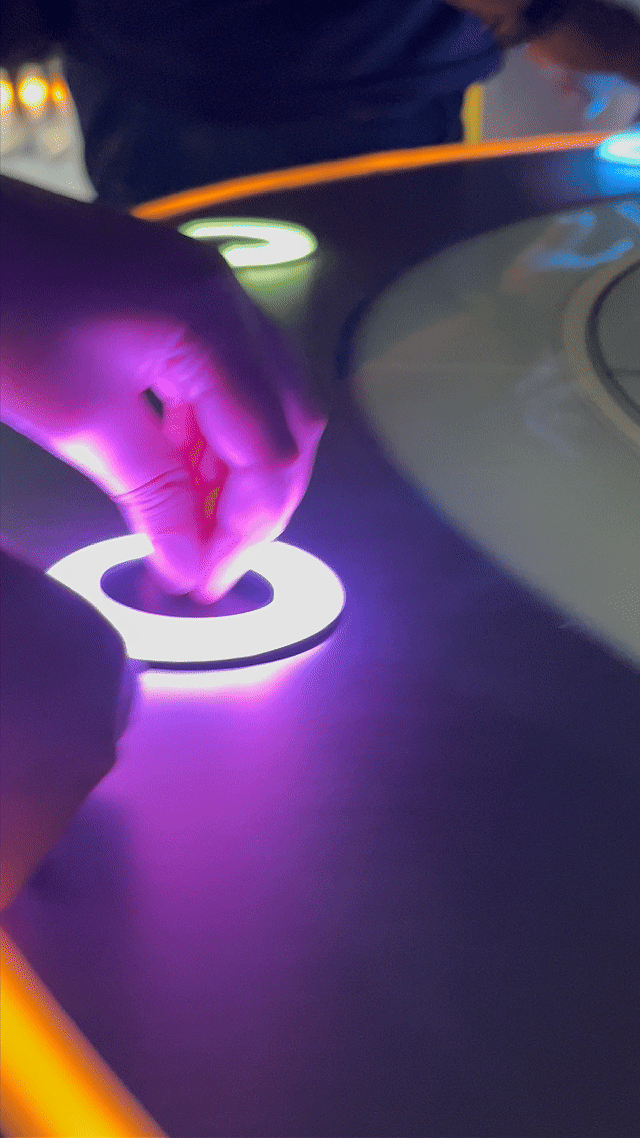 Visitantes interagem na ativação Pokémon Company | BGS 2025 – Experiência Megaevolução. Totens digitais da Phygital Solutions exibem o processo de escolha do Pokémon e da Mega Evolução, com público participando, cartões personalizados e iluminação temática do estande.