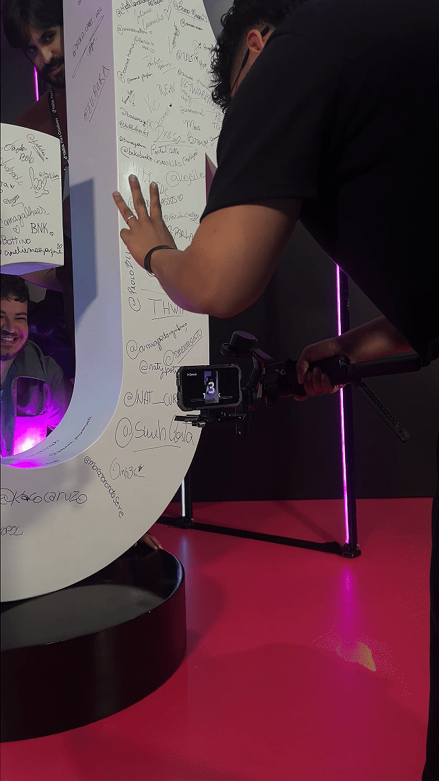 Participantes do evento TikTok para Criadores 2025 interagem com Roaming Booths da Phygital Solutions; vídeos gravados são exibidos em looping em uma Social Wall, criando engajamento contínuo durante o evento no Komplexo Tempo.