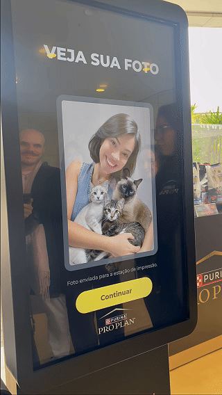Totem interativo da ativação Nestlé Purina com QR Code para envio de fotos pelo celular. A experiência utilizava inteligência artificial para gerar uma imagem personalizada do tutor ao lado do seu pet, com resultado final direcionado para impressão.