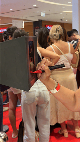 Participantes interagem com ativação Câmera Sign durante a inauguração da loja H&M no Shopping Rio Sul, criando vídeos personalizados com assinatura digital diretamente na lente da câmera.
