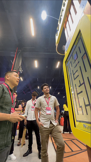 Participante joga ativação interativa da 99Entrega em um totem com joystick durante o VTEX DAY 2026, navegando em um labirinto estilo game para realizar entregas virtuais.