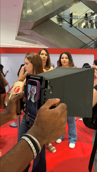 Participantes interagem com ativação Câmera Sign durante a inauguração da loja H&M no Shopping Rio Sul, criando vídeos personalizados com assinatura digital diretamente na lente da câmera.