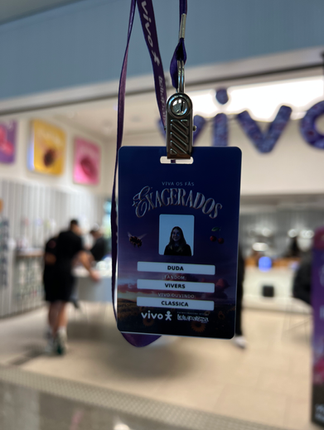 Pessoa interagindo com totem digital em loja da Vivo, realizando cadastro e tirando foto para geração de card personalizado impresso na hora durante ação pré-Lollapalooza.