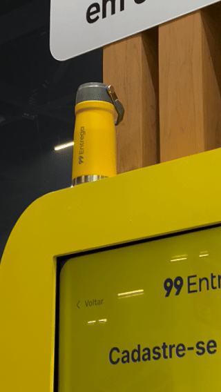Participante joga ativação interativa da 99Entrega em um totem com joystick durante o VTEX DAY 2026, navegando em um labirinto estilo game para realizar entregas virtuais.