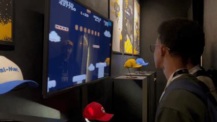 Visitantes interagem com o Museu RFID do Seu Boné na Brazil Promotion 2025, posicionando bonés históricos com tags RFID sobre suporte personalizado produzido em impressoras 3D pela Phygital Solutions, revelando histórias e curiosidades em tempo real.