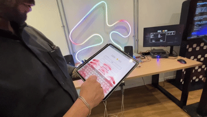 Autorama LED Phygital com traçado iluminado, controles 3D e pista personalizada. Participantes configuram clima e horário da corrida antes da largada.