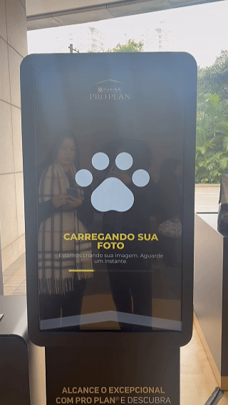 Totem interativo da ativação Nestlé Purina com QR Code para envio de fotos pelo celular. A experiência utilizava inteligência artificial para gerar uma imagem personalizada do tutor ao lado do seu pet, com resultado final direcionado para impressão.