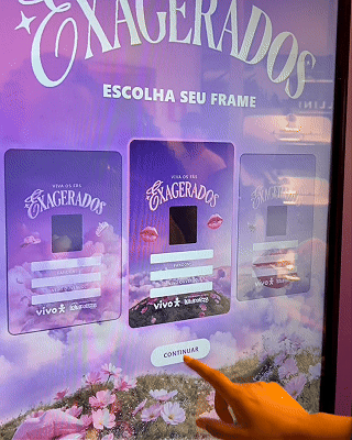 Pessoa interagindo com totem digital em loja da Vivo, realizando cadastro e tirando foto para geração de card personalizado impresso na hora durante ação pré-Lollapalooza.