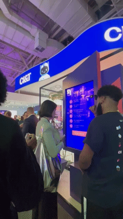 Público interage com totem AI Booth na ativação da CI&T na FEBRABAN. Participante escolhe como se imagina no futuro e recebe foto personalizada com tecnologia de inteligência artificial.