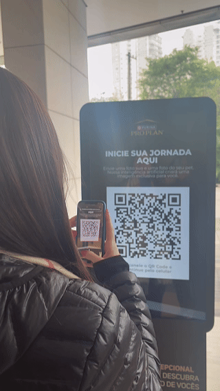 Totem interativo da ativação Nestlé Purina com QR Code para envio de fotos pelo celular. A experiência utilizava inteligência artificial para gerar uma imagem personalizada do tutor ao lado do seu pet, com resultado final direcionado para impressão.
