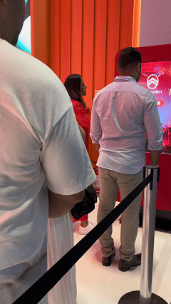 Visitante sendo fotografado em um totem da Citroën no Salão do Automóvel 2025, tendo sua imagem transformada por IA em um piloto da Fórmula E. A foto final aparece na tela ao lado, enquanto outro participante interage com a Roleta Digital personalizada com identidade da marca.