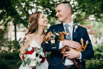 bride and groom smiling while holding dog