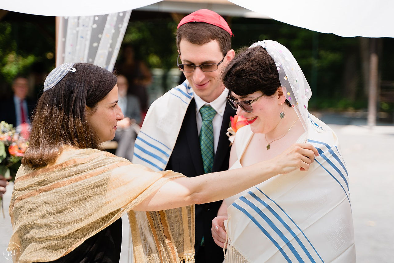 rabbi putting prayer shawl around bride and groom