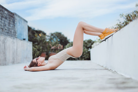 Dubai beauty and lifestyle photographer: Swimsuit model with orange trainers poses against a wall.