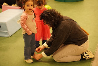 teacher tying young girls shoes