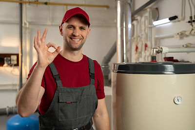 A skilled plumber in uniform is examining a residential water heater in a basement, ensuri