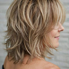 Girl standing on the side showing her blonde shaggy hair cut 