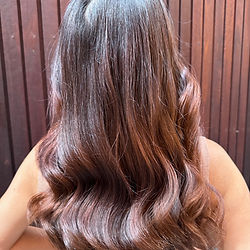 Girl with long brown hair showing off her soft curls from the back