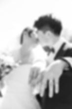 Bride and groom kissing, holding hands to show wedding rings. Bride in white dress, bouquet visible. Bright, backlit setting. Romantic mood /Mayfair Golf Course Wedding
