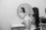 A woman in a white dress holds flowers, gazing at her reflection in a round mirror. Black and white setting, calm and contemplative mood at VanDusen Botanical Garden Wedding and Shaughnessy Restaurant wedding