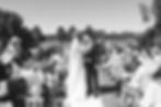 Bride and groom kiss in an outdoor wedding aisle surrounded by guests blowing bubbles. Joyful, sunny atmosphere with elegant attire at Mayfair Golf Course Wedding