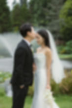 Groom kisses bride's forehead in a serene garden with a pond. Bride holds flowers, wearing a veil. Emotional and tender moment at VanDusen Botanical Garden Wedding and Shaughnessy Restaurant wedding
