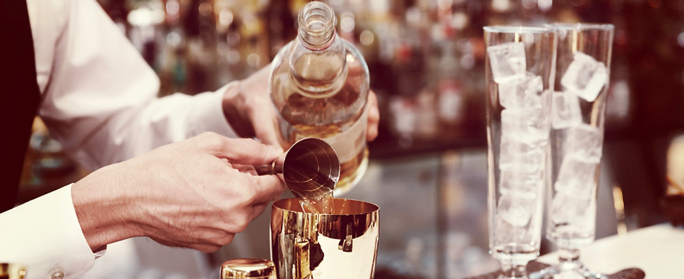 Bartender gibt Spirituose in den Mixbecher