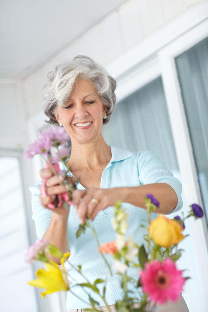 Smiling senior woman arranging a colorful bouquet of flowers