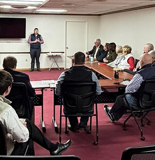 Legislator speaking at the front of a room of Blackwell Chamber members while seated community members listen during an Eggs & Issues breakfast event