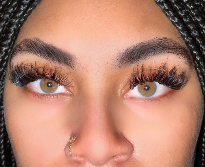 Close-up of long hybrid lash extensions on a caramel-skinned woman.