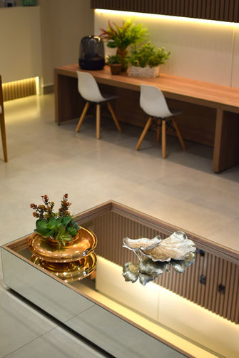 Ambiente de recepção moderno com mesa de madeira e cadeiras brancas.