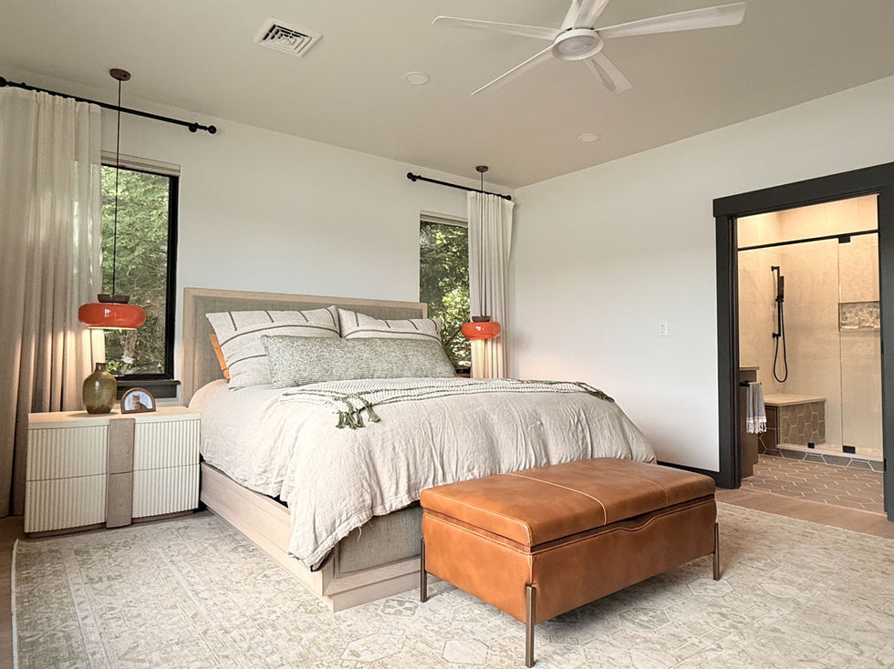 a bedroom with a green rug, tan bedding, orange bench and sconces