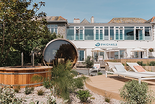 Sunlit spa patio with hot tub, white loungers and umbrellas in front of St Michaels hotel, calm seaside retreat