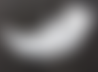 White paper fish or whale craft with fin-like folds on a dark background, softly lit and minimal.